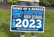 Student standing in front of his house with a DHS lawn sign